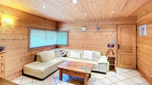 A cozy cabin interior with a wooden ceiling, a sofa set, a coffee table, and a window with blinds. - Cozy 4* chalet near slopes with parking and wifi for 14 guests (Le Corbier)