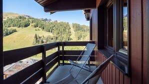 A balcony with a view of a mountainous landscape, a chair, and a window. - Apartment with balcony, parking, near La Plagne center (La Plagne 1800)