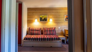 A bedroom with a wooden headboard, a bed with striped bedding, two bedside lamps, and two framed pictures on the wall. - Apartment with balcony, parking, near La Plagne center (La Plagne 1800)