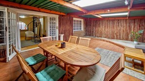 Una habitación amplia con una mesa de madera para comer, sillas y una escalera que sube a un nivel superior.