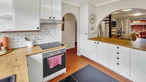 Una cocina moderna con armarios blancos, horno empotrado y encimera de madera.