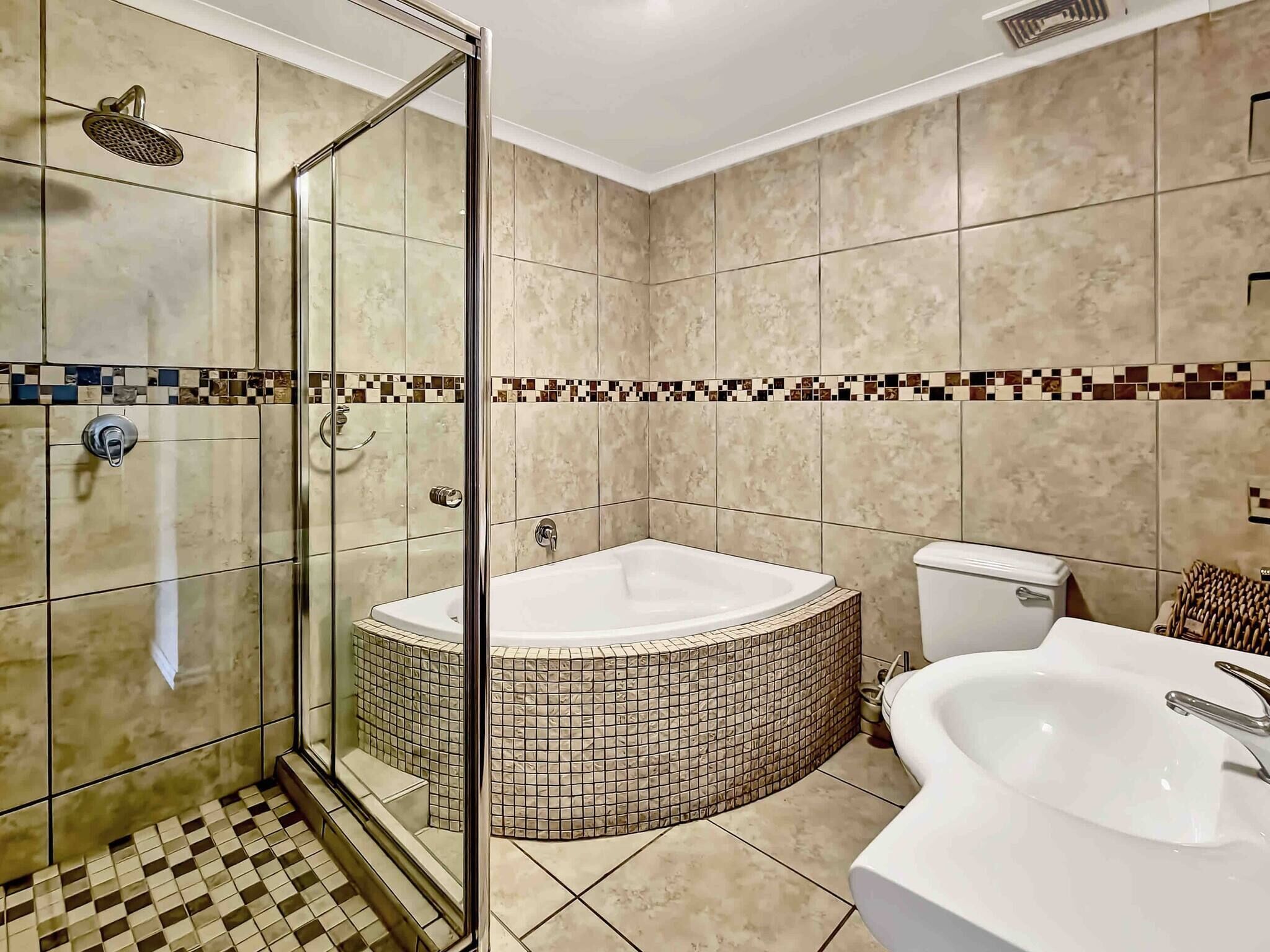 A bathroom with a glass-enclosed shower, a freestanding bathtub, and a sink.