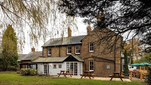 A traditional stone building with a large garden, picnic tables, and a covered seating area. - The Olde Coach House Inn  (Rugby)