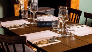 A dining table set with wine glasses, water glasses, and cutlery, with a menu and a 'RESERVE' sign visible. - The Olde Coach House Inn  (Rugby)