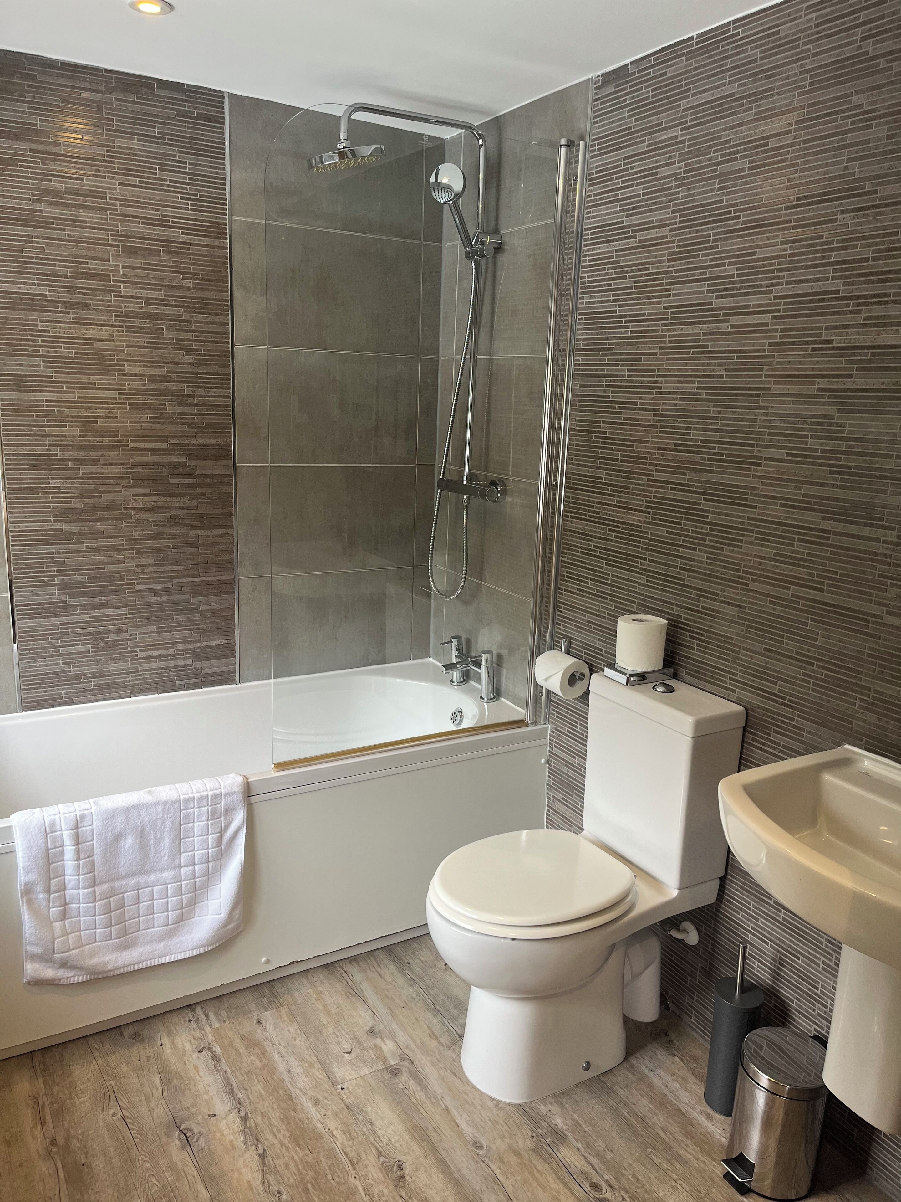 A modern bathroom with a glass-enclosed shower, a bathtub, a toilet, and a sink.