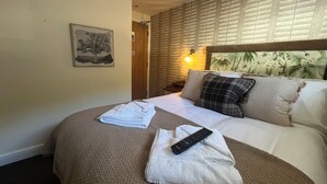 A neatly made bed with a remote control and folded towels on a textured brown bedspread. - The Olde Coach House Inn  (Rugby)