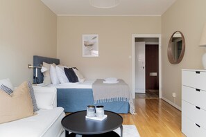 Relax in this serene bedroom with a comfortable bed, sofa, and coffee table, surrounded by a large mirror and artwork.