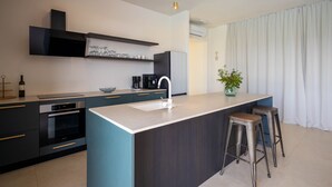 A modern kitchen with a central island, bar stools, and a built-in oven. - Villa Santa Lucia (Sveti Filip i Jakov)