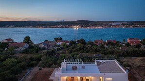 A modern house with a flat roof, large windows, and a patio area. - Villa Santa Lucia (Sveti Filip i Jakov)