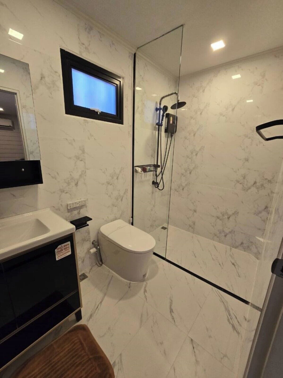 A modern bathroom with a glass-enclosed shower, a toilet, and a sink.