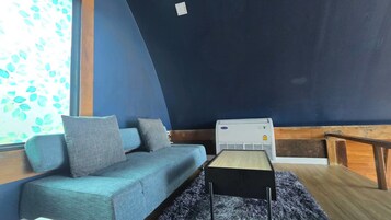 Una habitación con un sofá azul, una mesita y un equipo de aire acondicionado.