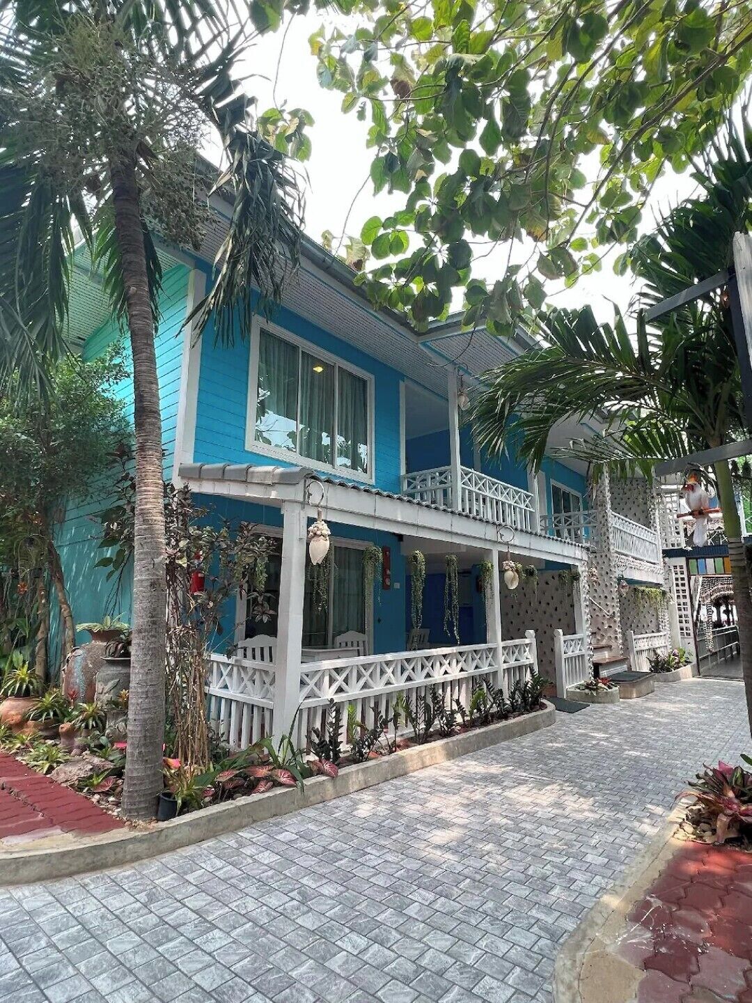 A two-story building with a blue facade, white railings, and a covered porch area.