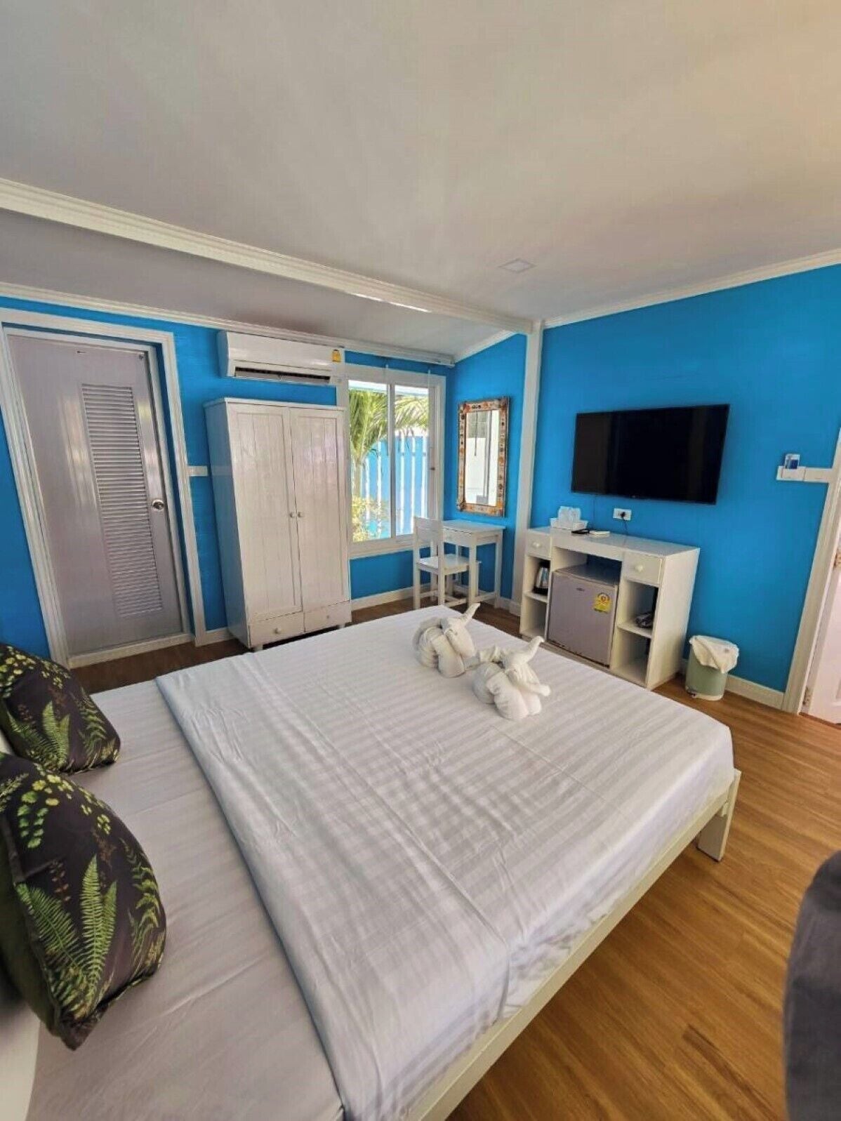 Ein Schlafzimmer mit Bett, Schreibtisch, Fernseher und Kleiderschrank.