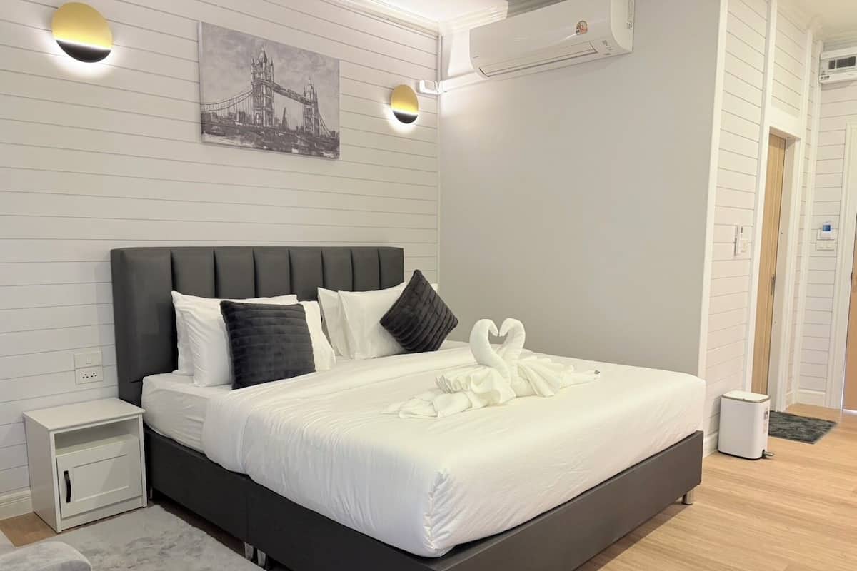 Quarto de hotel moderno com uma cama grande, uma mesa de cabeceira, ar condicionado fixado na parede e um quadro com uma imagem de uma ponte.