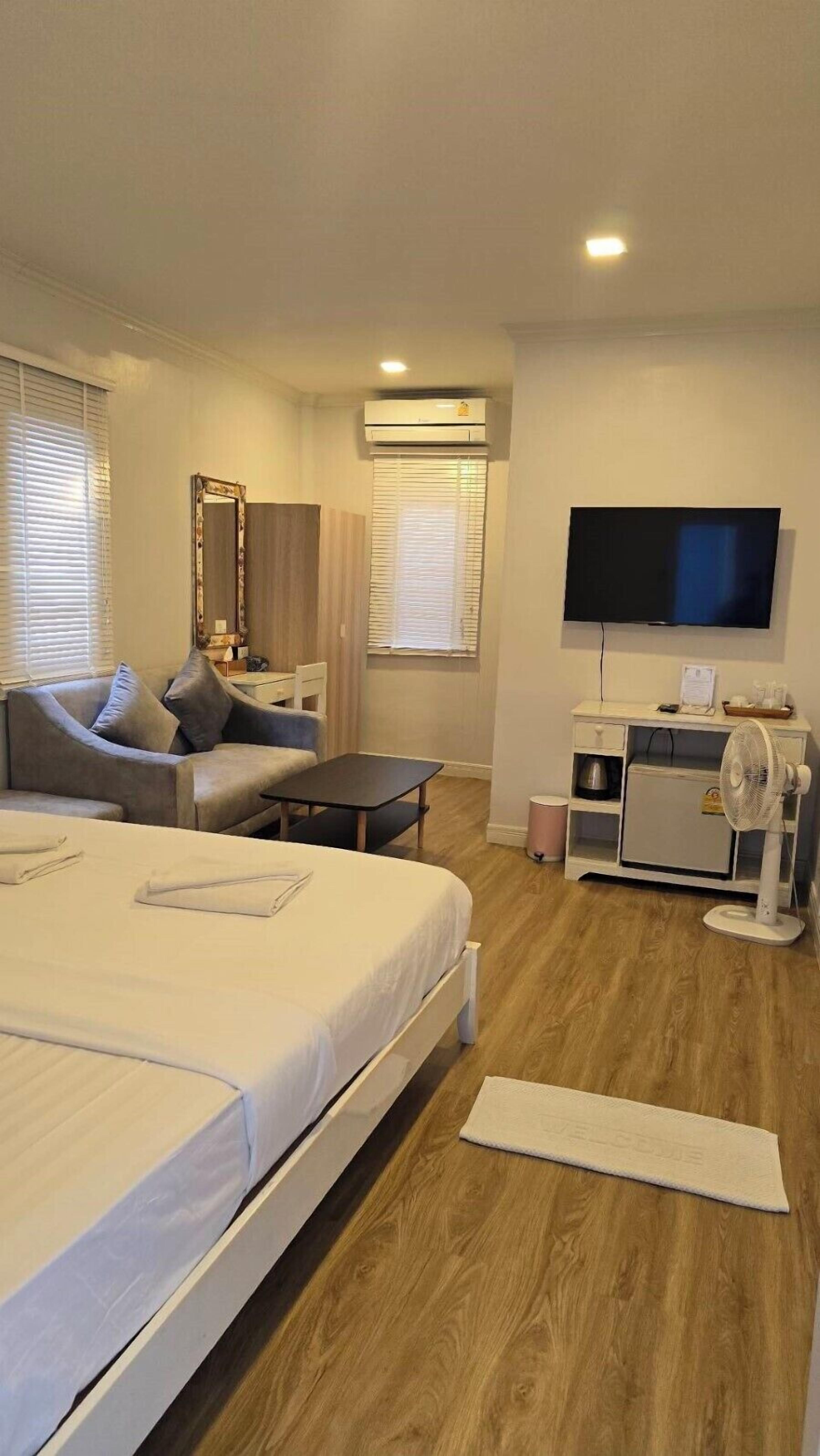 A hotel room with a bed, a sofa, a TV, and a desk.