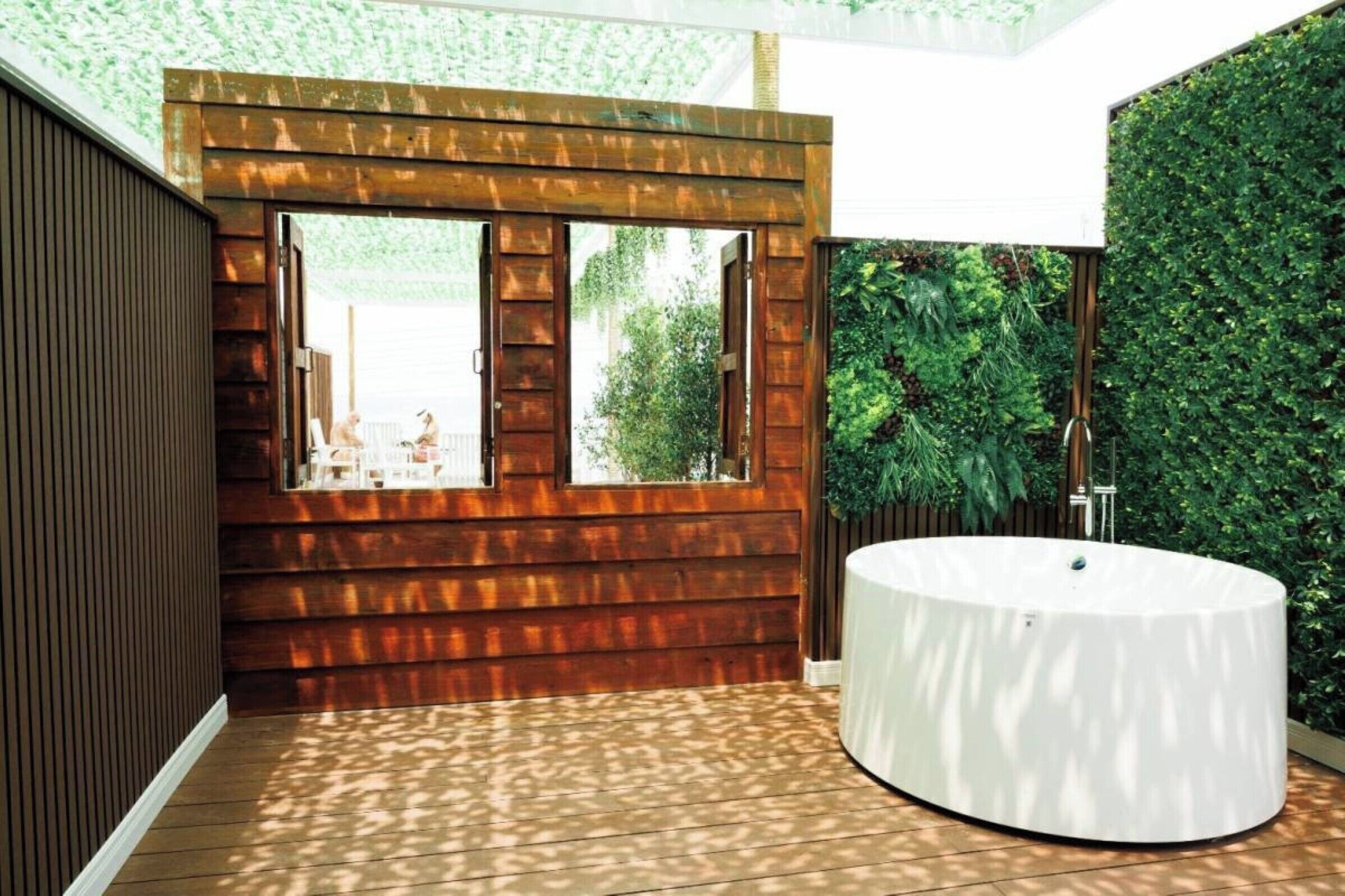 Ein modernes Badezimmer mit Holzvertäfelung, einem großen Fenster und einer runden Badewanne.
