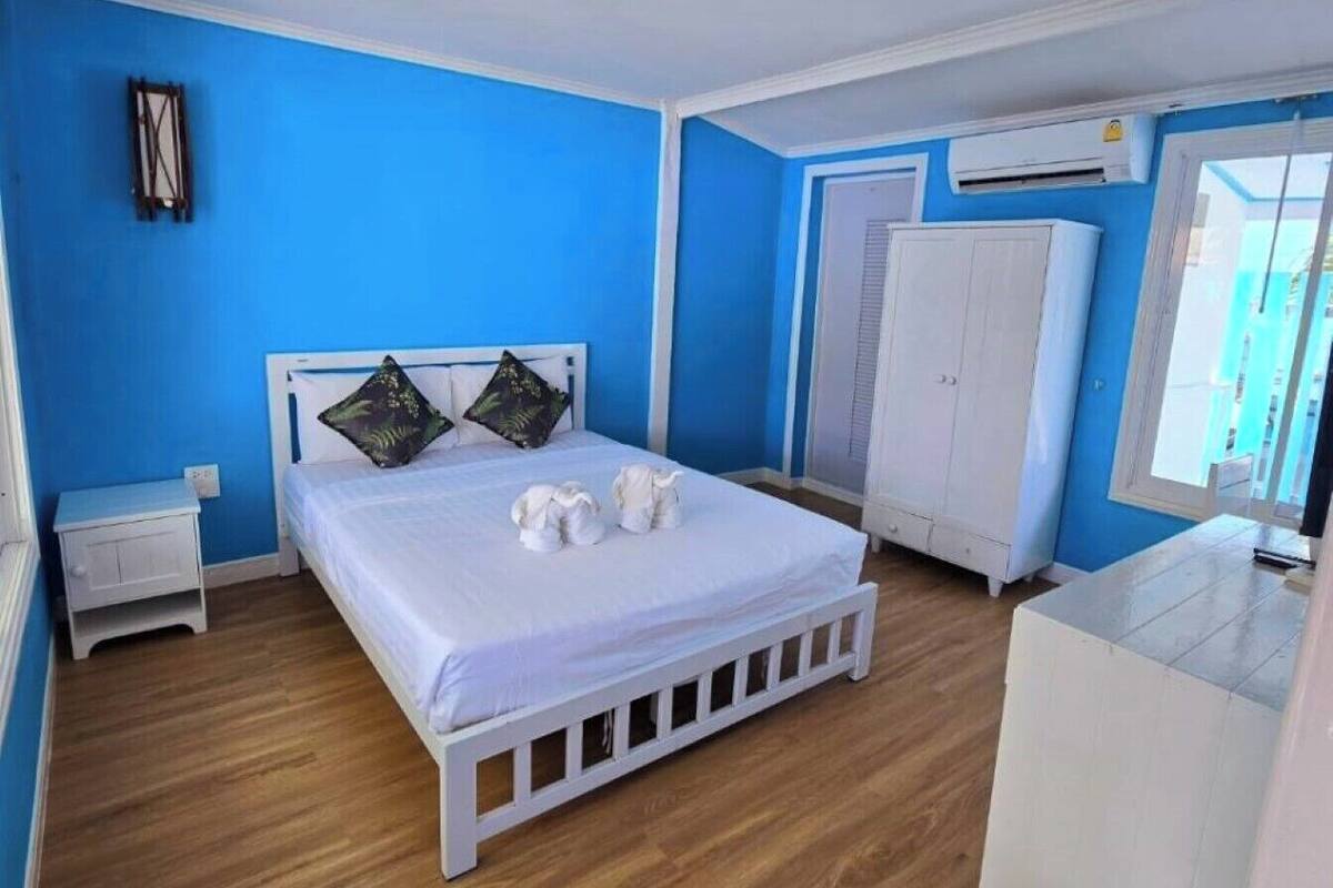 Quarto com cama, guarda-roupa branco e uma mesinha.