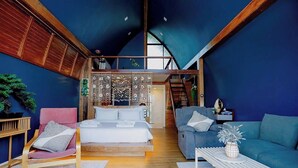 Un intérieur moderne avec une chambre à coucher de style loft, un coin salon confortable et un escalier menant à un niveau supérieur.