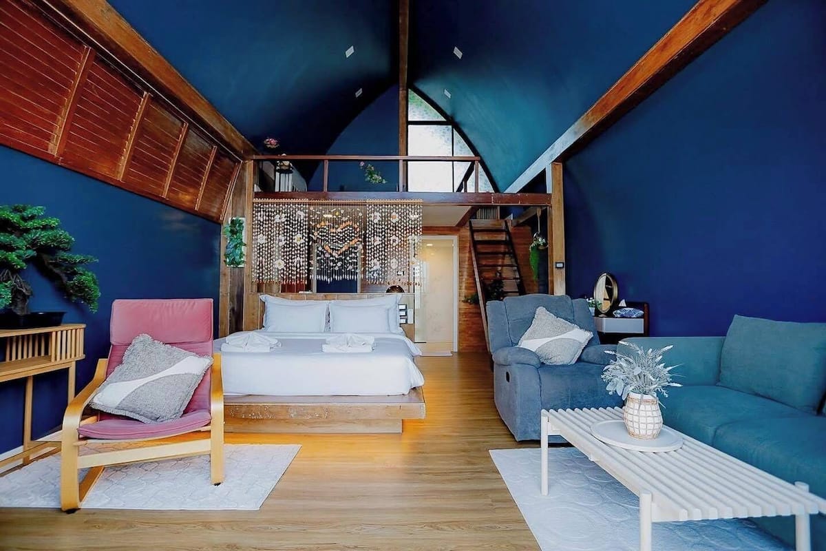 Um interior moderno com um quarto estilo loft, uma área de estar aconchegante e uma escada que leva a um andar superior.