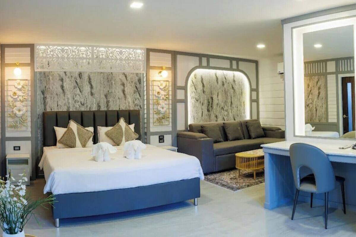 Quarto de hotel moderno com uma cama grande, um sofá, uma escrivaninha e um pequeno frigorífico.