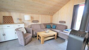Una habitación acogedora con sofá, mesa de centro, lámpara, chimenea y un tablero de ajedrez sobre un aparador.