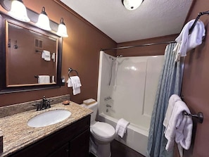 A bathroom with a sink, mirror, shower, and toilet.