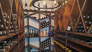 Une cave à vin avec des étagères et des présentoirs en bois, contenant diverses bouteilles de vin et de spiritueux.