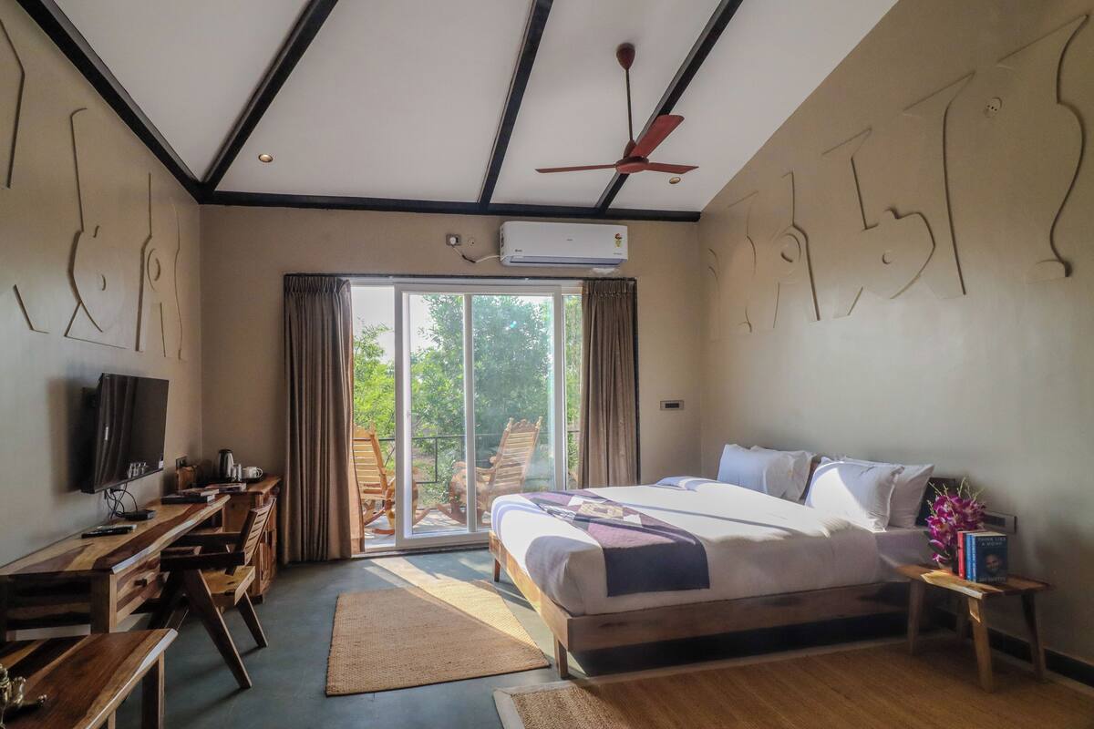 Une chambre à coucher avec un lit, un bureau et une chaise, une télévision et un ventilateur de plafond.