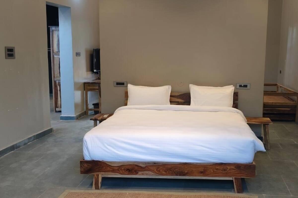 Une chambre à coucher avec un cadre de lit en bois, du linge de lit blanc et une petite table de chevet.