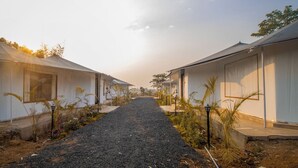 A row of white mobile homes with a gravel path between them, surrounded by greenery. - Shiv Ganga Kanha Resort (Baihar)
