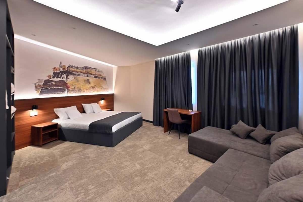 Et moderne hotelværelse med en stor seng, et skrivebord, en sofa og et billede på væggen.