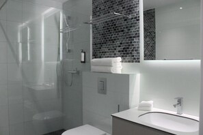 A modern bathroom with a glass-enclosed shower, a white sink, and a large mirror above the vanity.