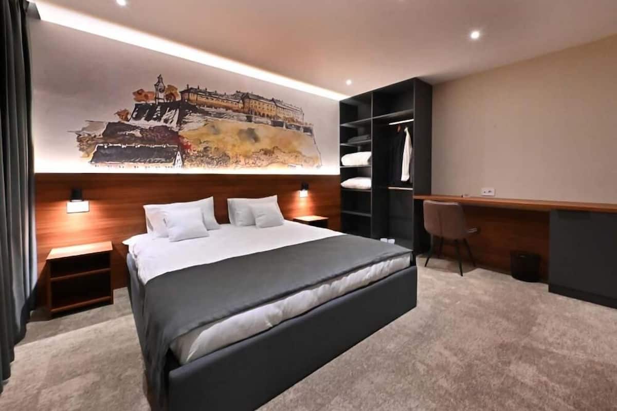 Et moderne hotelværelse med en stor seng, et skrivebord og et garderobeskab.