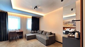Une chambre d’hôtel moderne avec un canapé d’angle, un bureau et un lit.