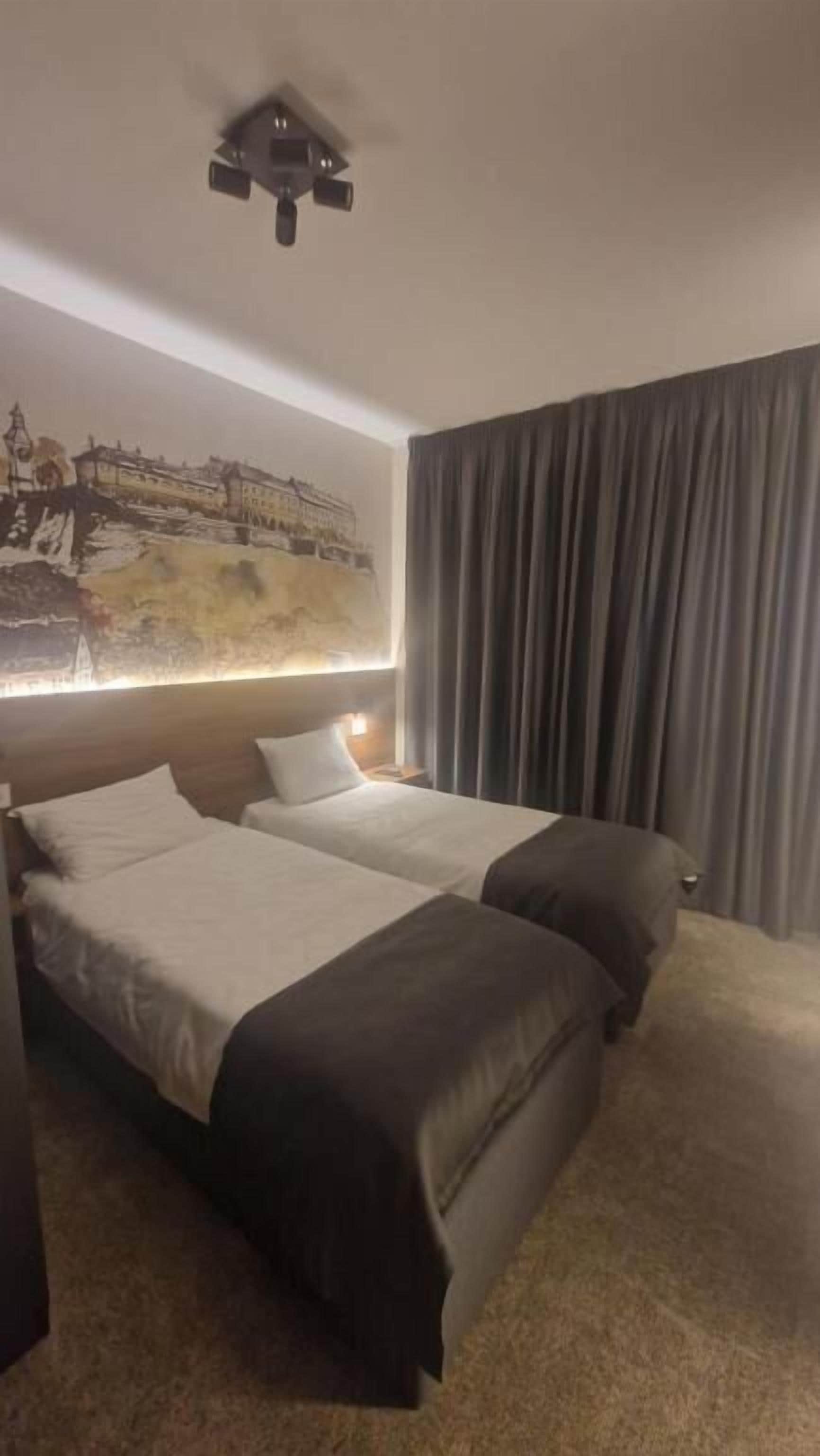 Een hotelkamer met twee bedden, een groot schilderij aan de muur en een gordijn voor het raam.