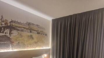 Een hotelkamer met twee bedden, een groot schilderij aan de muur en een gordijn voor het raam.
