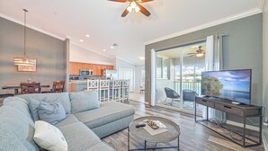 A modern living room with a sectional sofa, a coffee table, a TV on a stand, and a ceiling fan.