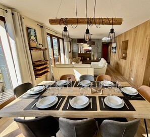 Zona pranzo con tavolo in legno apparecchiata per sei persone, circondata da sedie.
