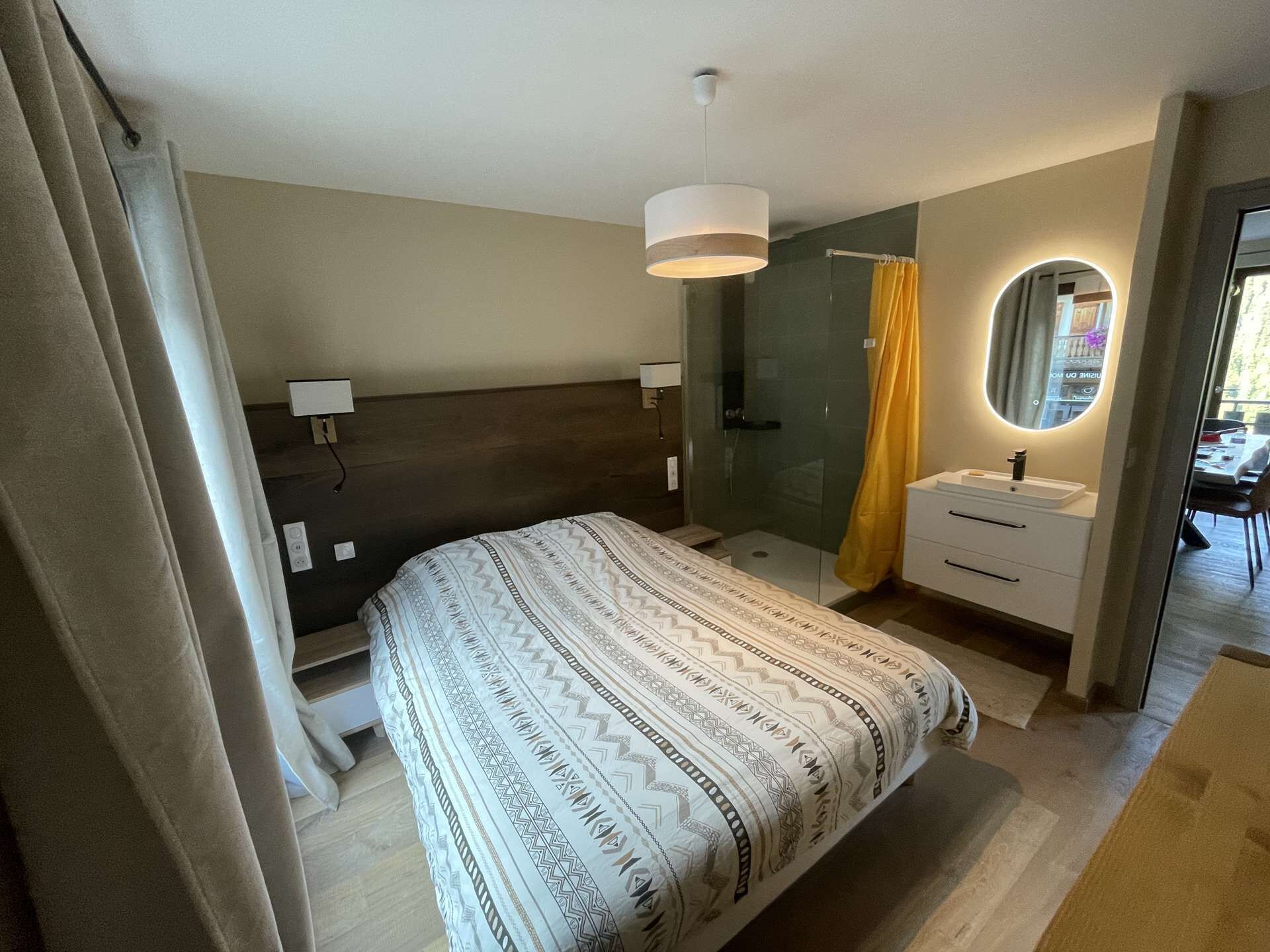 A modern bedroom with a bed, bedside table, and a shower area.