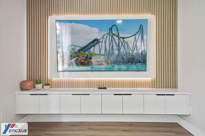 Una sala moderna con un televisor de pantalla plana grande montado en un mueble blanco.