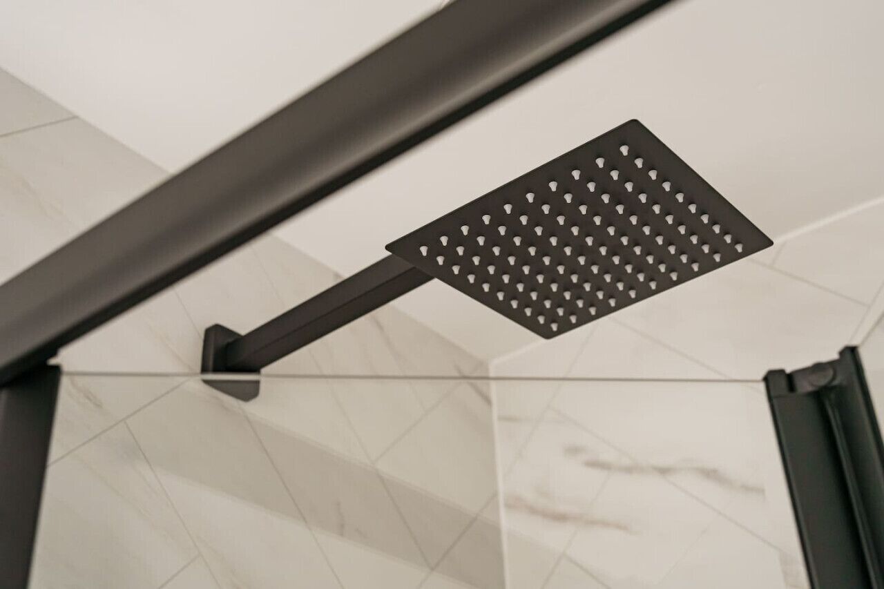 A modern showerhead with a geometric design, mounted on a dark metal frame.
