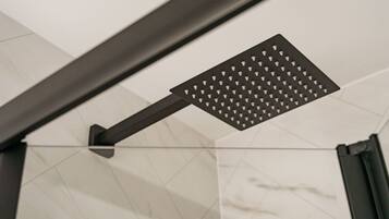 A modern showerhead with a geometric design, mounted on a dark metal frame.
