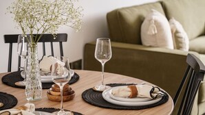 Una mesa de comedor preparada con platos, vasos y un florero.