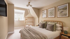 Un dormitorio con cama, una mesita de noche con lámpara, una silla colgante y cuadros con motivos botánicos en la pared.