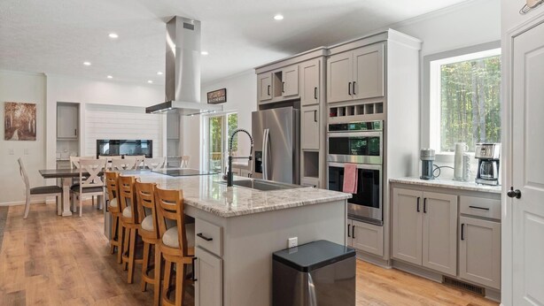 Una cocina moderna con una isla central, electrodomésticos de acero inoxidable y un comedor con sillas de madera.