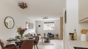 A modern kitchen with a dining area, featuring a round table, chairs, and a vase with flowers.