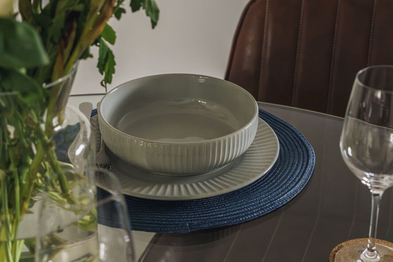 Une table à manger avec un bol et une assiette posés sur un set de table bleu.