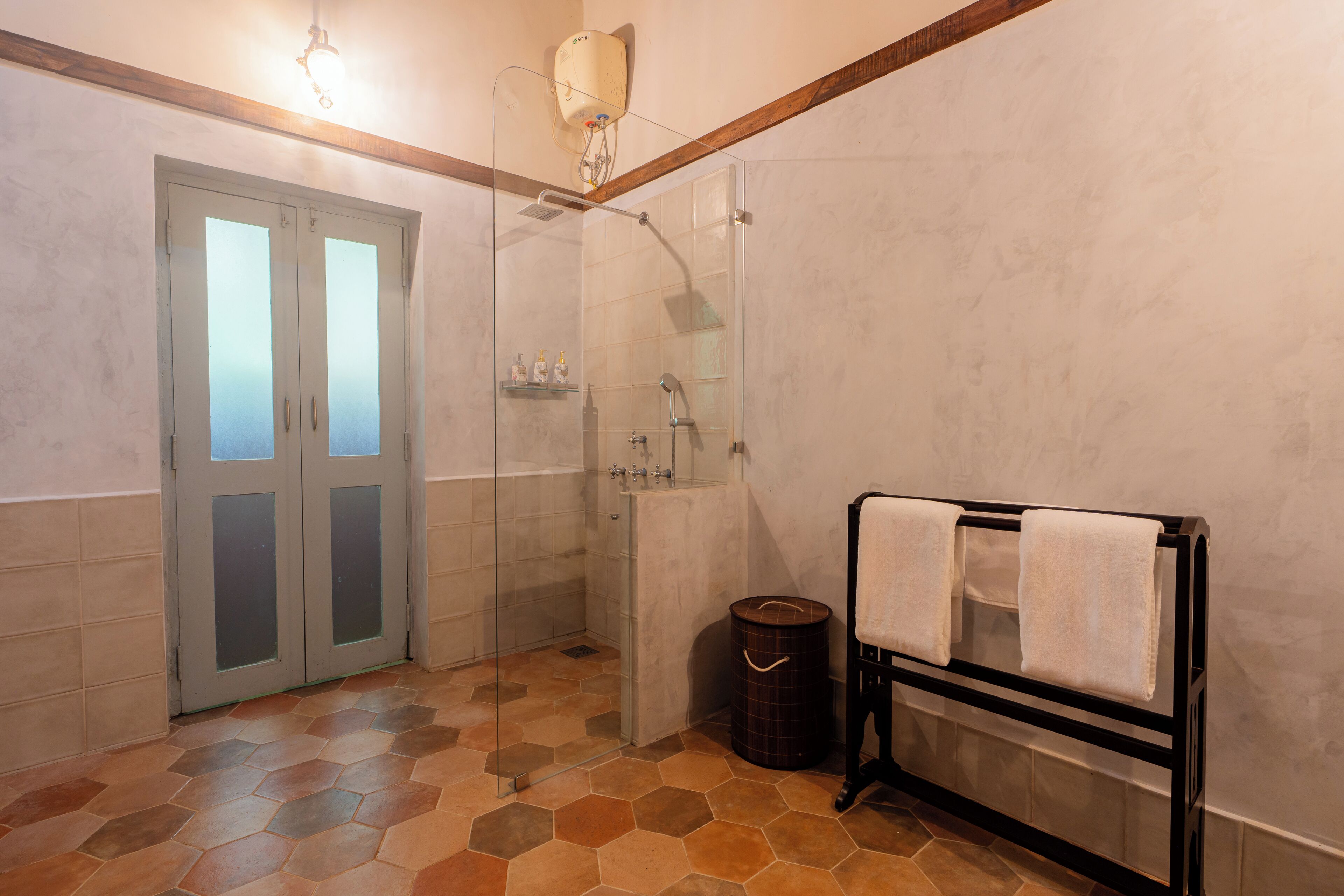 A bathroom with a glass shower enclosure, a towel rack, and a waste bin.