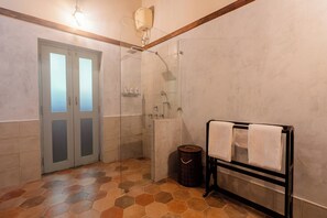 A bathroom with a glass shower enclosure, a towel rack, and a waste bin. - Mansao Curtorim- CGH Earth SAHA (Curtorim)