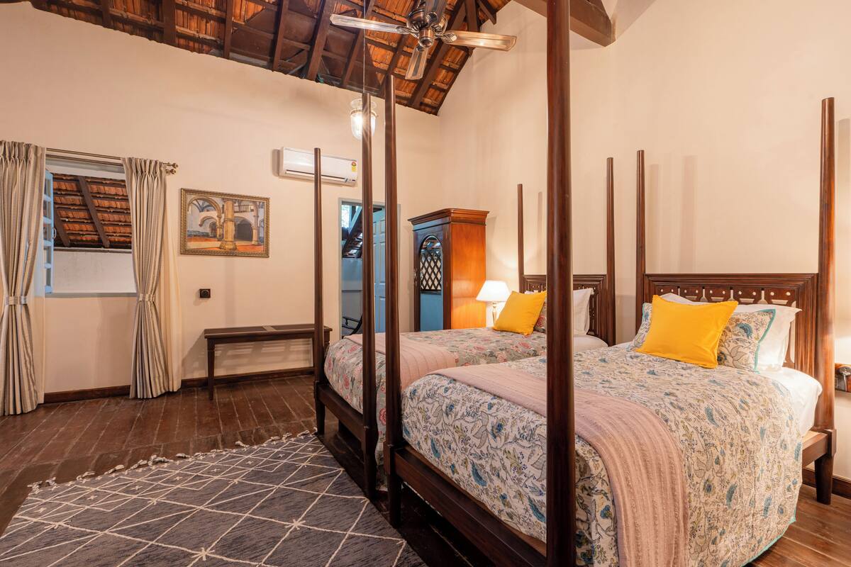 Een hemelbed met een bloemenbedekking, een houten hoofdbord en een nachtkastje met een lamp.